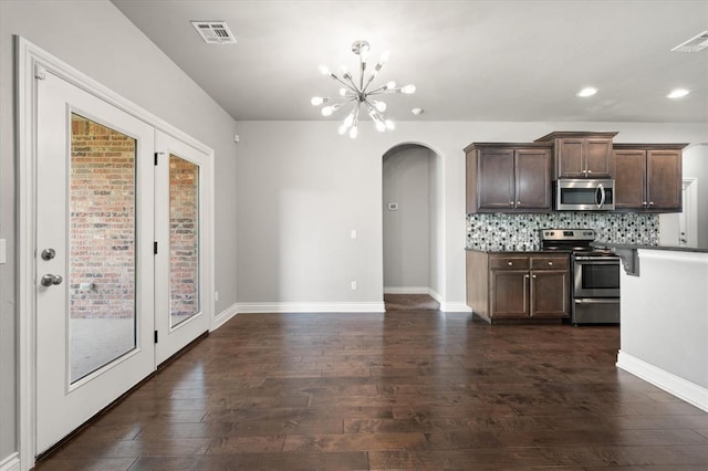 8309 NW 139th Ter, Oklahoma City, OK 73142 - kitchen featuring appliances with stainless steel finishes, arched walkways, dark wood-style floors, dark brown cabinetry, and a chandelier