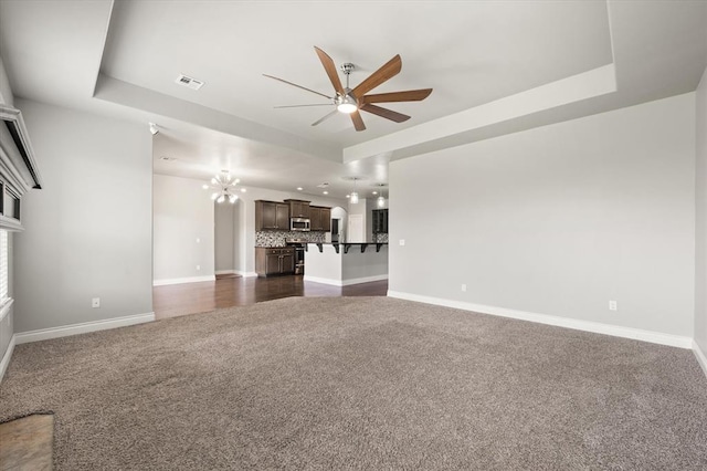 8309 NW 139th Ter, Oklahoma City, OK 73142 - unfurnished living room featuring dark carpet, a ceiling fan, a chandelier, and a raised ceiling