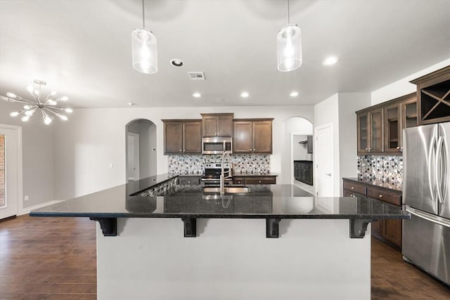 8309 NW 139th Ter, Oklahoma City, OK 73142 - kitchen featuring stainless steel appliances, arched walkways, decorative backsplash, a kitchen bar, and recessed lighting