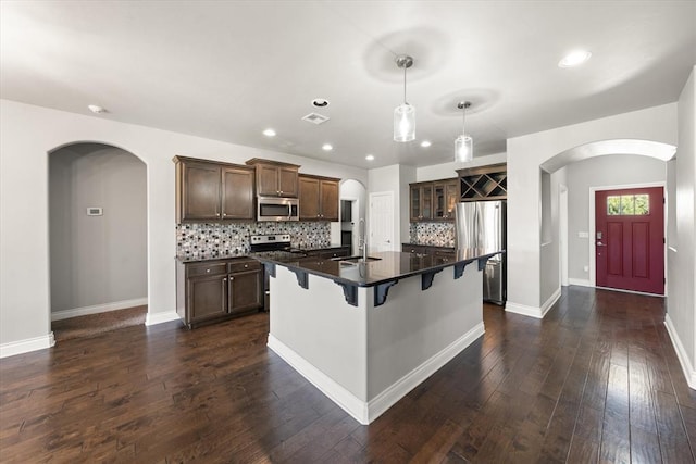 8309 NW 139th Ter, Oklahoma City, OK 73142 - kitchen with stainless steel appliances, arched walkways, dark countertops, a breakfast bar, and backsplash