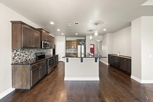 8309 NW 139th Ter, Oklahoma City, OK 73142 - kitchen with stainless steel appliances, arched walkways, dark wood-style flooring, dark brown cabinets, and recessed lighting