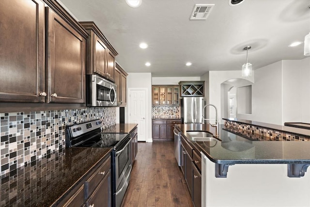 8309 NW 139th Ter, Oklahoma City, OK 73142 - kitchen featuring stainless steel appliances, arched walkways, tasteful backsplash, dark wood-style flooring, and a spacious island