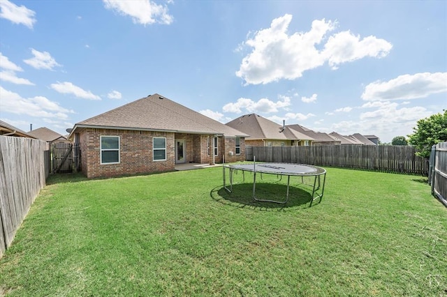 8309 NW 139th Ter, Oklahoma City, OK 73142 - rear view of property featuring brick siding, a fenced backyard, a trampoline, and a shingled roof