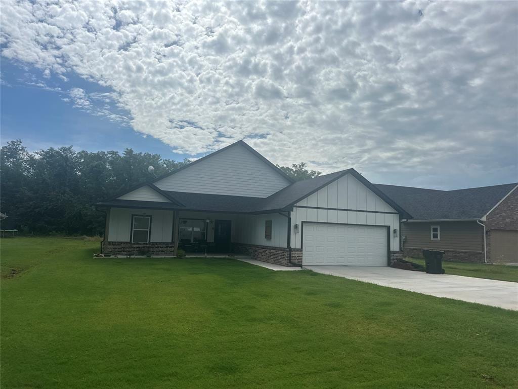 914 S Ash St, Luther, OK 73054 - view of front of home featuring a front lawn, board and batten siding, concrete driveway, and a garage