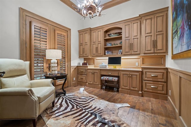 18816 Otter Creek Dr, Edmond, OK 73012 - home office with built in desk, a chandelier, dark wood-type flooring, a wainscoted wall, and a decorative wall