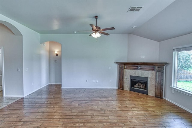 816 Lakeview Dr, Moore, OK 73160 - unfurnished living room featuring ceiling fan, arched walkways, wood finished floors, a tile fireplace, and lofted ceiling