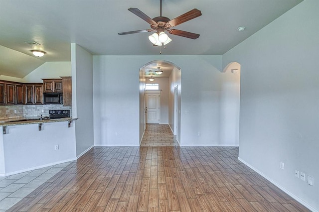 816 Lakeview Dr, Moore, OK 73160 - unfurnished living room with arched walkways, ceiling fan, light wood finished floors, and vaulted ceiling