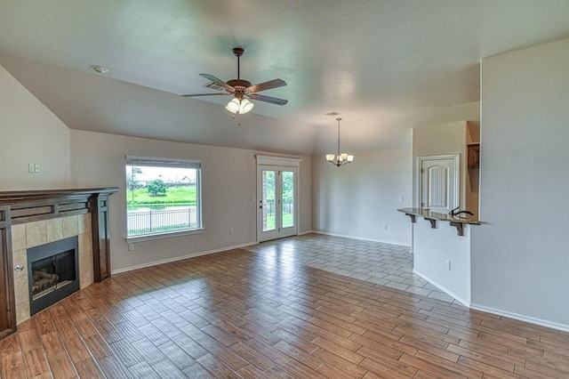 816 Lakeview Dr, Moore, OK 73160 - unfurnished living room with a tile fireplace, lofted ceiling, wood finished floors, a ceiling fan, and a chandelier