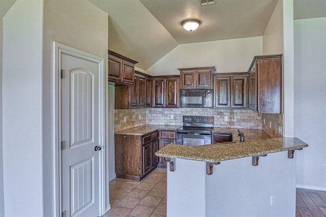 816 Lakeview Dr, Moore, OK 73160 - kitchen with black appliances, a peninsula, a breakfast bar area, backsplash, and lofted ceiling