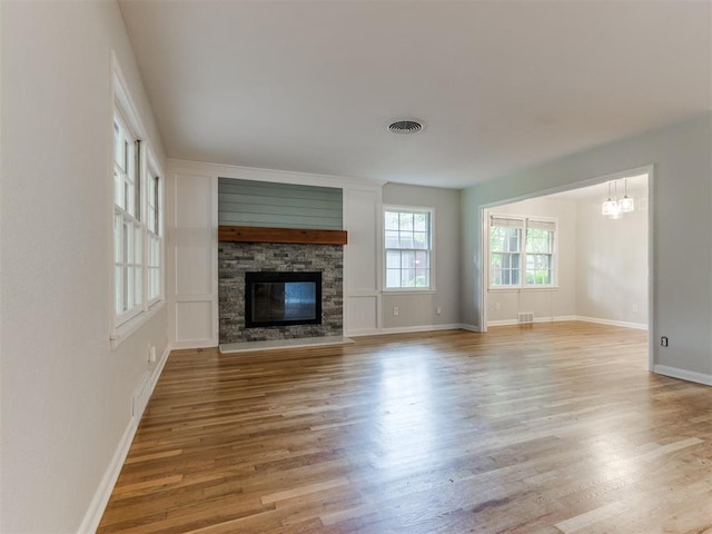 1213 Leslie Ln, Norman, OK 73069 - unfurnished living room with wood finished floors, a stone fireplace, and a chandelier