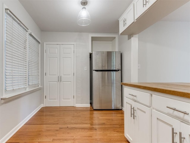 1213 Leslie Ln, Norman, OK 73069 - kitchen with freestanding refrigerator, light wood-style flooring, white cabinets, and butcher block counters