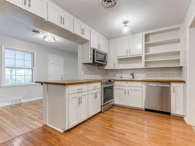 1213 Leslie Ln, Norman, OK 73069 - kitchen with appliances with stainless steel finishes, butcher block counters, light wood-style floors, backsplash, and open shelves