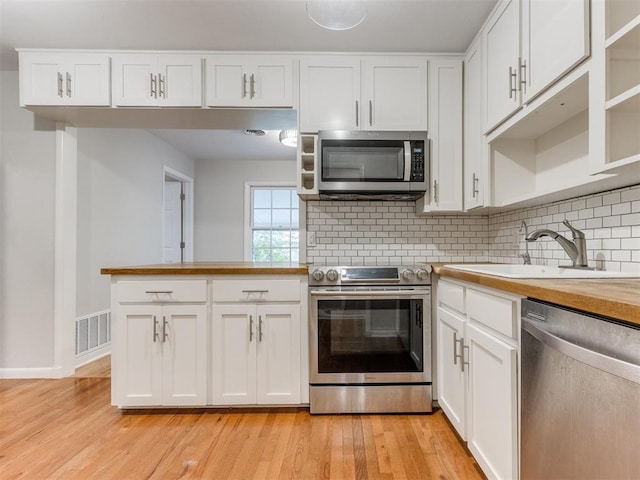 1213 Leslie Ln, Norman, OK 73069 - kitchen featuring stainless steel appliances, light wood-style floors, tasteful backsplash, butcher block counters, and white cabinetry