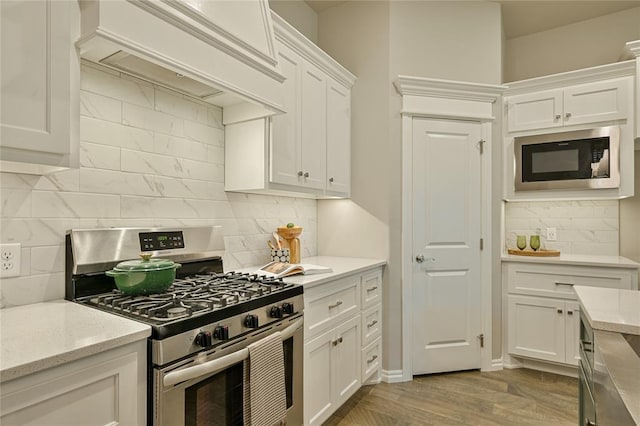 3808 Palmetto Trl, Oklahoma City, OK 73179 - kitchen with stainless steel gas range, built in microwave, tasteful backsplash, white cabinets, and custom exhaust hood