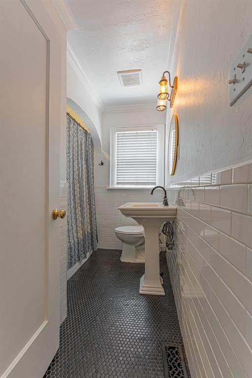 416 W Hill St, Oklahoma City, OK 73118 - full bath featuring tile walls, tile patterned flooring, a wainscoted wall, ornamental molding, and a textured ceiling