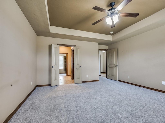 2801 SE 5th St, Moore, OK 73160 - unfurnished bedroom featuring a tray ceiling, light carpet, and a ceiling fan