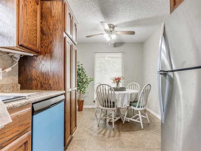12501 SW 6th St, Yukon, OK 73099 - kitchen featuring freestanding refrigerator, dishwasher, brown cabinetry, light countertops, and a textured ceiling