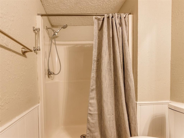 12501 SW 6th St, Yukon, OK 73099 - full bathroom with a textured wall, a textured ceiling, a shower with shower curtain, wainscoting, and a decorative wall