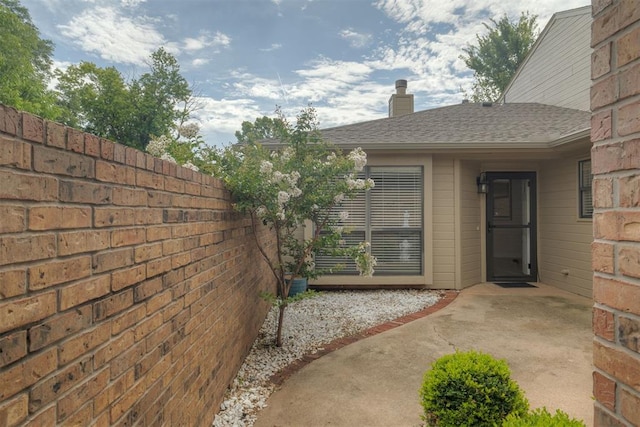 12210 High Meadow Ct, Oklahoma City, OK 73170 - view of exterior entry with a chimney, a patio, and roof with shingles