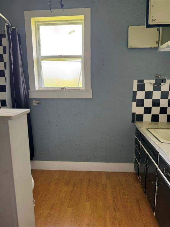 223 N Market St, Cordell, OK 73632 - full bath featuring wood finished floors, vanity, and a shower with curtain