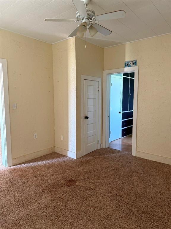 223 N Market St, Cordell, OK 73632 - carpeted spare room featuring ceiling fan and a textured wall