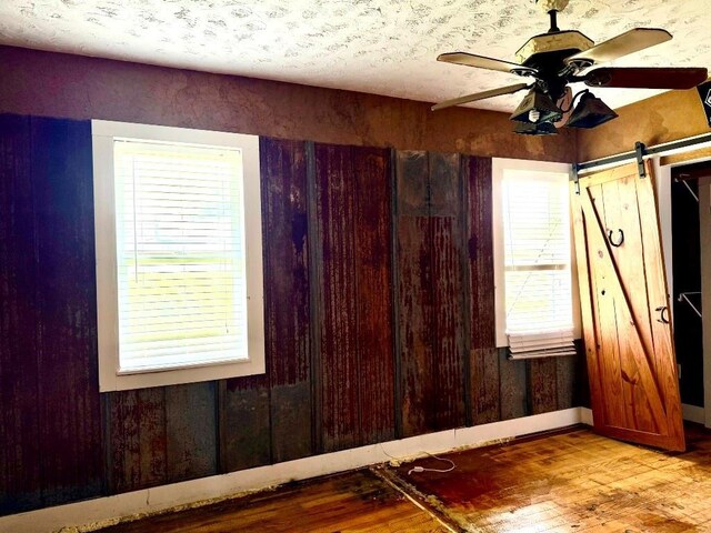 223 N Market St, Cordell, OK 73632 - empty room with wood finished floors, a ceiling fan, and a barn door
