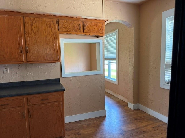 223 N Market St, Cordell, OK 73632 - kitchen with dark wood-style flooring, dark countertops, a textured wall, and brown cabinets