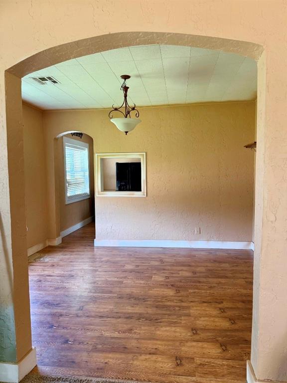 223 N Market St, Cordell, OK 73632 - unfurnished living room featuring arched walkways, wood finished floors, and a textured wall