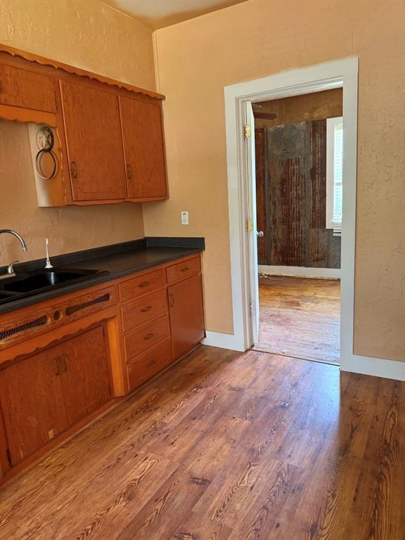 223 N Market St, Cordell, OK 73632 - kitchen featuring light wood finished floors, dark countertops, and brown cabinetry