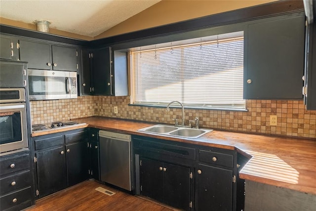 2728 NE 99th St, Oklahoma City, OK 73131 - kitchen featuring appliances with stainless steel finishes, vaulted ceiling, decorative backsplash, dark wood finished floors, and dark cabinetry