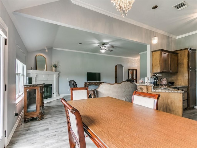 1401 Baycharter St, Norman, OK 73071 - dining room with light wood finished floors, crown molding, a glass covered fireplace, lofted ceiling, and a ceiling fan