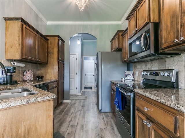 1401 Baycharter St, Norman, OK 73071 - kitchen with stainless steel appliances, arched walkways, tasteful backsplash, light wood-style flooring, and stone counters