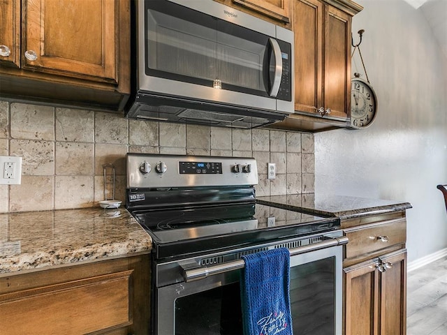 1401 Baycharter St, Norman, OK 73071 - kitchen with appliances with stainless steel finishes, decorative backsplash, brown cabinets, and stone countertops