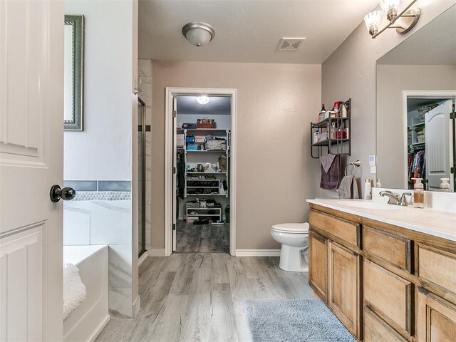 1401 Baycharter St, Norman, OK 73071 - bathroom with a walk in closet, vanity, wood finished floors, a garden tub, and a shower stall