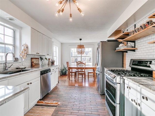 2647 NW 24th St, Oklahoma City, OK 73107 - kitchen with appliances with stainless steel finishes, brick floors, open shelves, white cabinetry, and healthy amount of natural light
