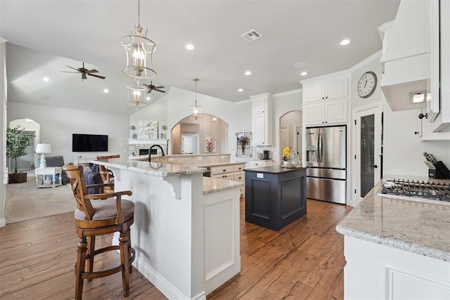 19804 Dalemead Way, Edmond, OK 73012 - kitchen featuring stainless steel appliances, a ceiling fan, a large island with sink, arched walkways, and light wood-type flooring