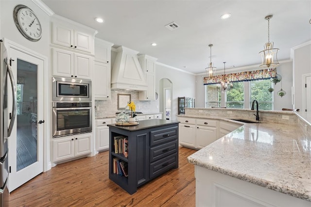 19804 Dalemead Way, Edmond, OK 73012 - kitchen with appliances with stainless steel finishes, custom exhaust hood, a spacious island, white cabinets, and crown molding