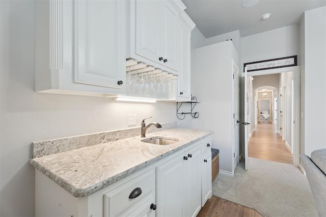 19804 Dalemead Way, Edmond, OK 73012 - kitchen with white cabinets, light wood-type flooring, light stone countertops, arched walkways, and light carpet