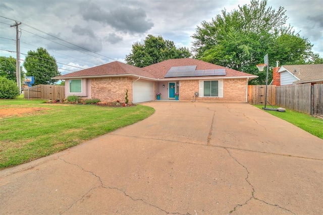 100 Three Oaks Dr, Midwest City, OK 73130 - ranch-style house featuring an attached garage, solar panels, driveway, brick siding, and a gate