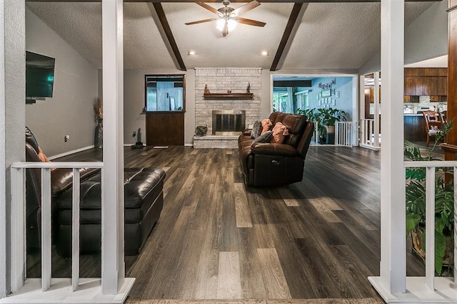 100 Three Oaks Dr, Midwest City, OK 73130 - living area with dark wood-style flooring, ceiling fan, a textured ceiling, and a stone fireplace