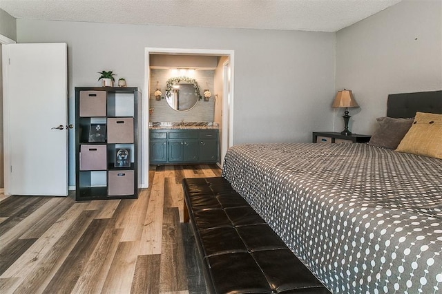 100 Three Oaks Dr, Midwest City, OK 73130 - bedroom featuring wood finished floors, ensuite bath, and a textured ceiling