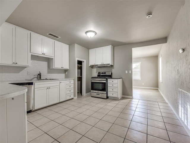 6617 NW 31st St, Bethany, OK 73008 - kitchen with appliances with stainless steel finishes, under cabinet range hood, tasteful backsplash, light tile patterned floors, and white cabinets