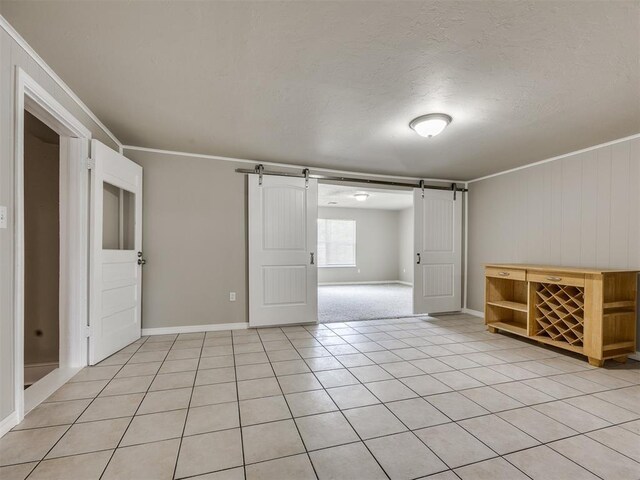 6617 NW 31st St, Bethany, OK 73008 - unfurnished room featuring a barn door, crown molding, and light tile patterned flooring