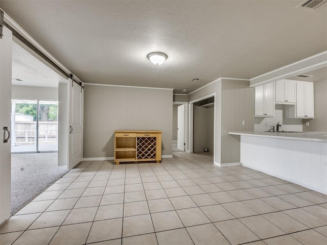 6617 NW 31st St, Bethany, OK 73008 - unfurnished living room with a barn door, a textured ceiling, crown molding, and light tile patterned floors