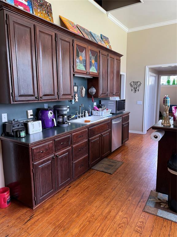 342532 E 1020th Rd, Meeker, OK 74855 - kitchen featuring appliances with stainless steel finishes, crown molding, light wood-style flooring, dark countertops, and dark brown cabinets