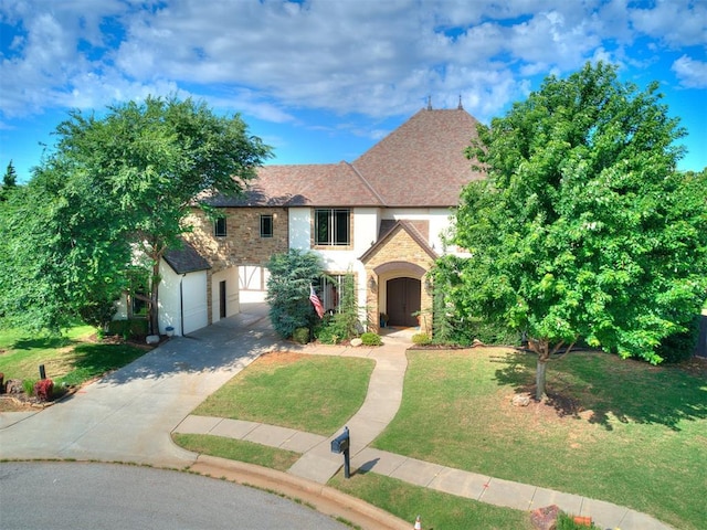 4109 Slate Bridge Rd, Edmond, OK 73034 - tudor-style house featuring stone siding, concrete driveway, a front lawn, a garage, and stucco siding