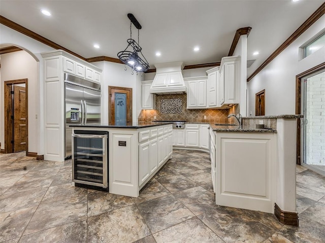 4109 Slate Bridge Rd, Edmond, OK 73034 - kitchen with wine cooler, custom exhaust hood, stainless steel appliances, crown molding, and arched walkways