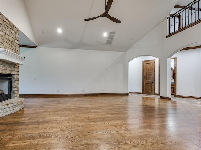 4109 Slate Bridge Rd, Edmond, OK 73034 - unfurnished living room featuring high vaulted ceiling, arched walkways, a ceiling fan, a fireplace, and wood finished floors