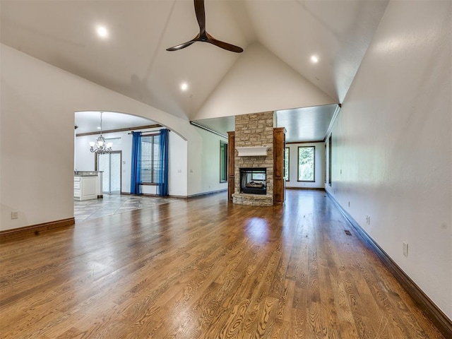 4109 Slate Bridge Rd, Edmond, OK 73034 - unfurnished living room with ceiling fan, a stone fireplace, high vaulted ceiling, a chandelier, and arched walkways