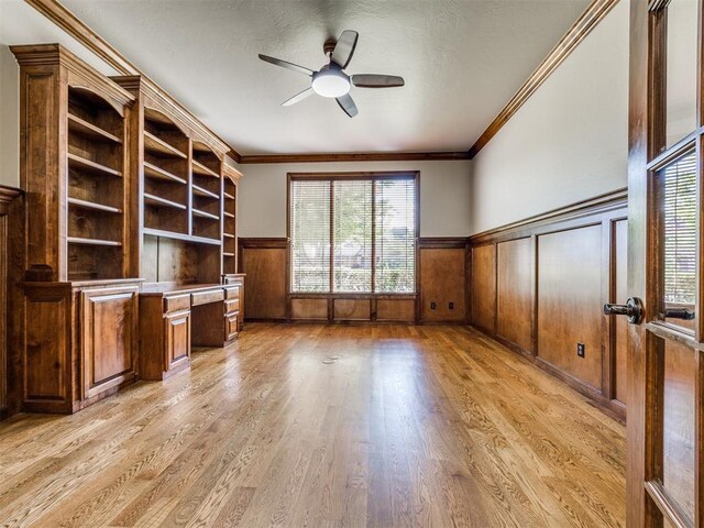4109 Slate Bridge Rd, Edmond, OK 73034 - unfurnished living room featuring built in study area, wainscoting, ceiling fan, light wood-type flooring, and healthy amount of natural light